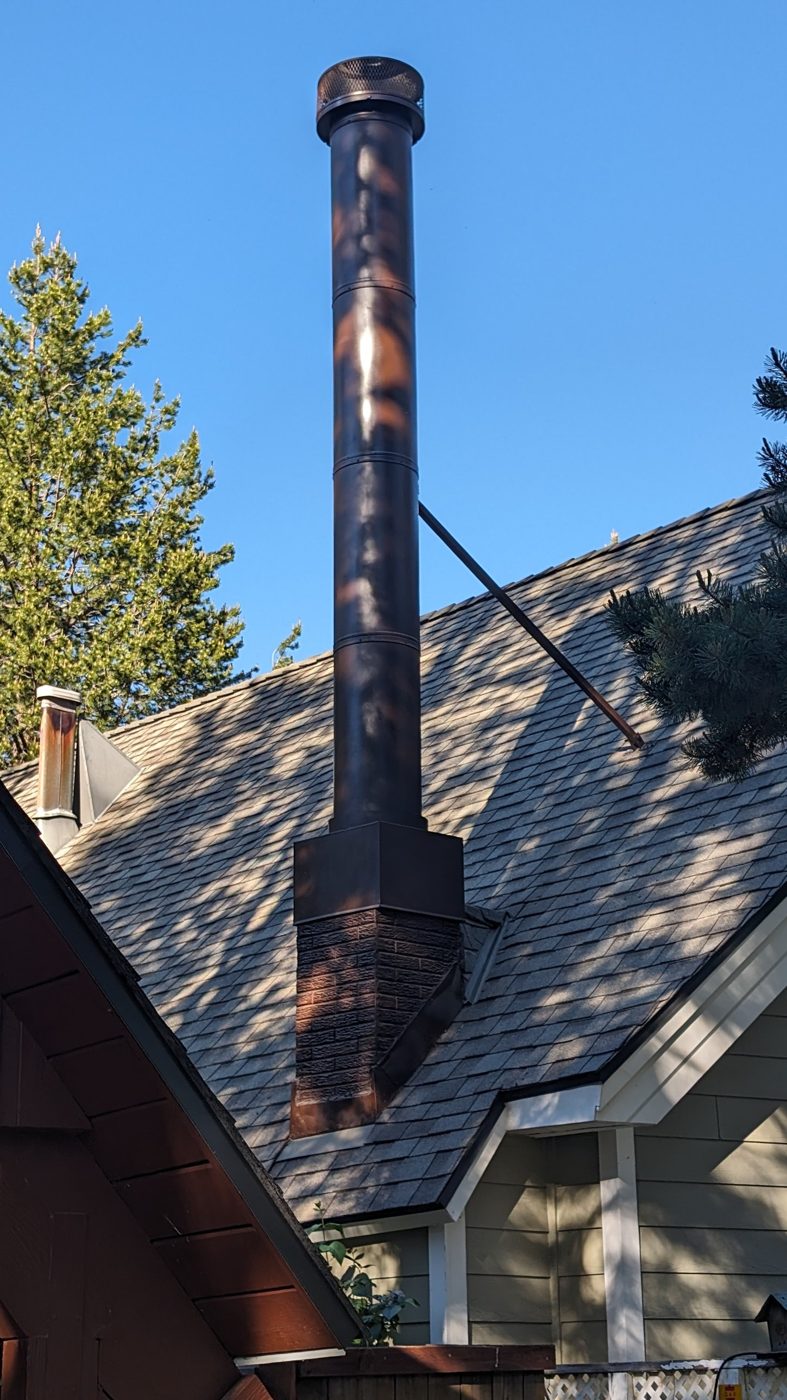 Tall chimney pipe braced to a shingle roof