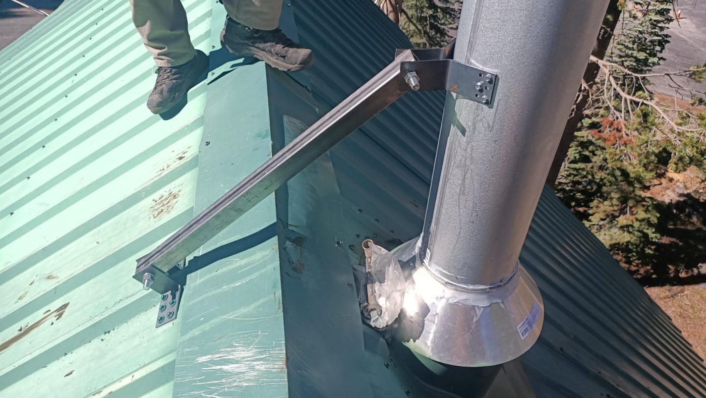 Heavy-duty steel chimney brace on a metal roof